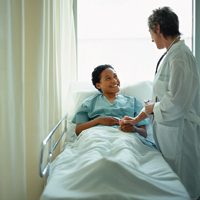 Patient in hospital bed smiling and holding hands with doctor standing beside bed